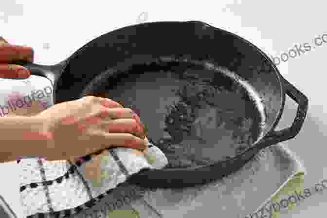 A Person Seasoning A Cast Iron Pan With Oil, Illustrating The Importance Of Proper Seasoning Cast Iron Cuisine: Essential Tools For Your Iron Cookware: Making Cast Iron Pan Food